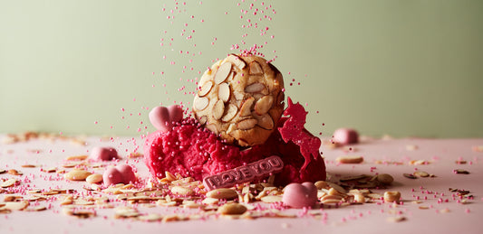 A dessert highlighting an Almond Croissant Biscuit is presented with a layer of bright pink ice cream, showered in pink sprinkles and embellished with heart-shaped decorations. A small plaque inscribed with "I LOVE YOU" echoes the whimsical charm of this dreamy treat by She means Biscuits.