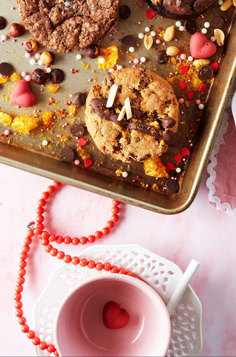 Assorted chocolate cookies on a baking tray with a pink background